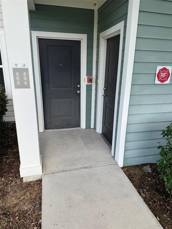 An exterior view shows two dark doors on a concrete walkway with apartment signage — 2460 ANN ROU ROAD UNIT 606, TAVARES, FL