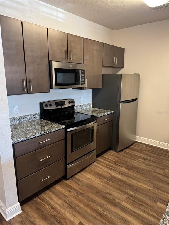 A kitchen features dark wood cabinets, stainless steel appliances, and granite countertops — 2460 ANN ROU ROAD UNIT 606, TAVARES, FL