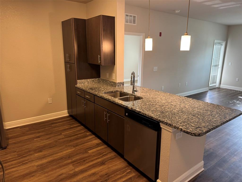 A kitchen features dark wood cabinets, granite countertops, stainless steel appliances, and wood-look flooring — 2460 ANN ROU ROAD UNIT 606, TAVARES, FL