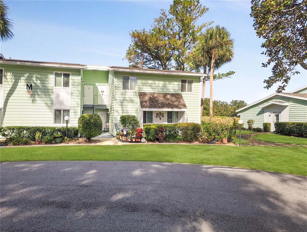 A two-story light green apartment building features a central staircase and landscaped front yard — 487 MIDWAY DRIVE UNIT B, OCALA, FL