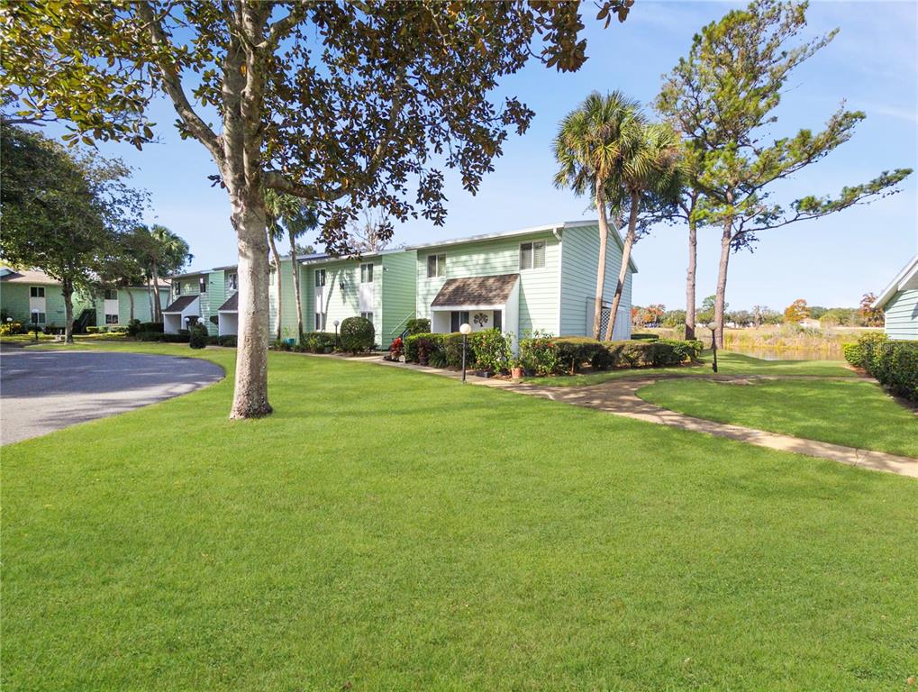 A two-story light green apartment building sits on a grassy lawn with mature trees — 487 MIDWAY DRIVE UNIT B, OCALA, FL