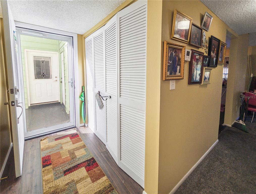 An entryway features a wood-look floor, a colorful rug, white louvered closet doors, and framed photos — 487 MIDWAY DRIVE UNIT B, OCALA, FL