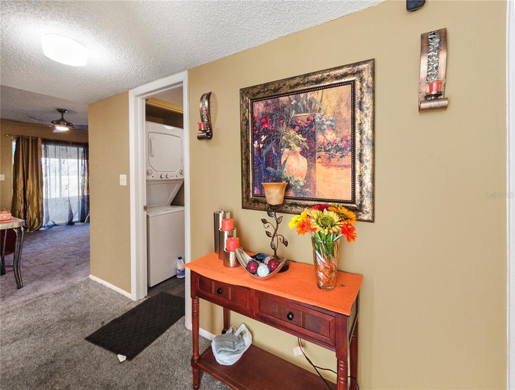 A hallway features a wooden console table with decor beneath a framed painting and sconces — 487 MIDWAY DRIVE UNIT B, OCALA, FL