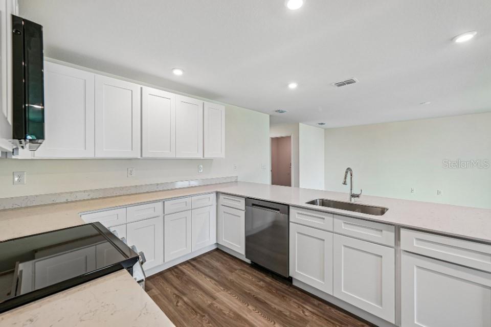 A modern kitchen features white shaker cabinets, quartz countertops, and stainless steel appliances — 16065 MINORCA DRIVE, PUNTA GORDA, FL