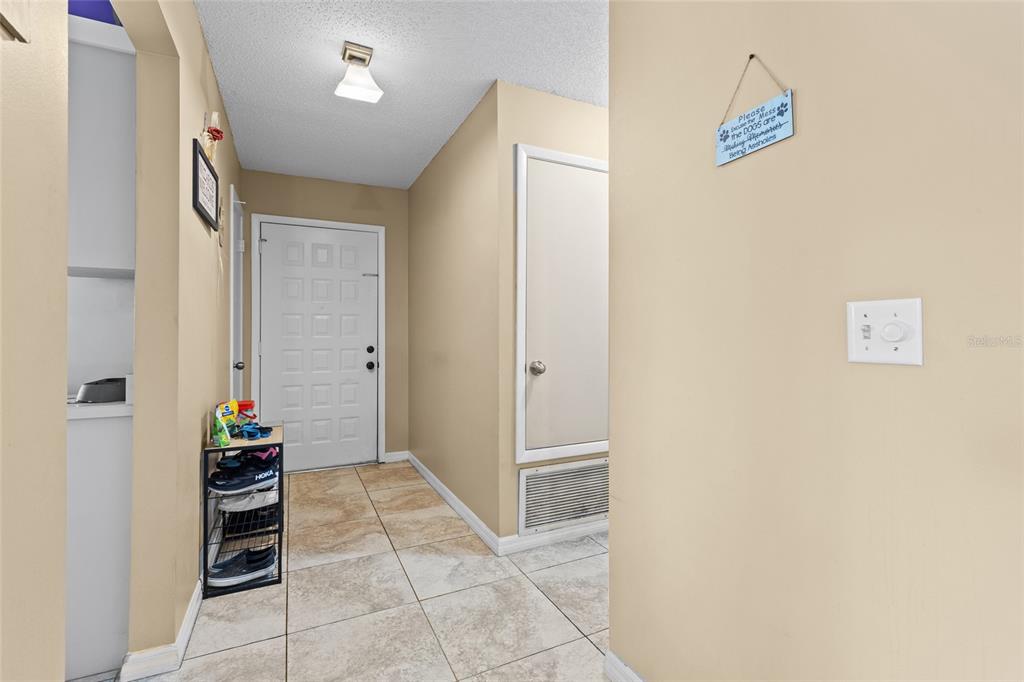 A tiled entryway features a white front door, a shoe rack, and a wall sign — 601 ALBANY COURT, LONGWOOD, FL