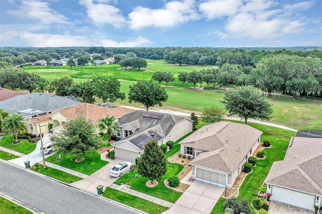 An aerial view shows suburban houses with solar panels and driveways bordering a golf course — 3601 ARLINGTON RIDGE BOULEVARD, LEESBURG, FL