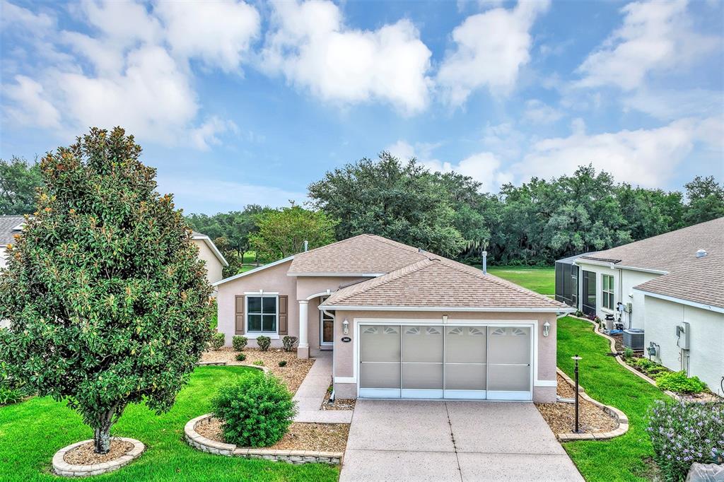 A single-story house with a beige stucco exterior, a tan shingled roof, and a garage — 3601 ARLINGTON RIDGE BOULEVARD, LEESBURG, FL