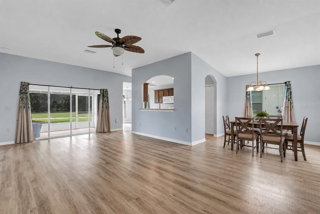 An open-concept living and dining area with light wood-look flooring and a ceiling fan — 3601 ARLINGTON RIDGE BOULEVARD, LEESBURG, FL