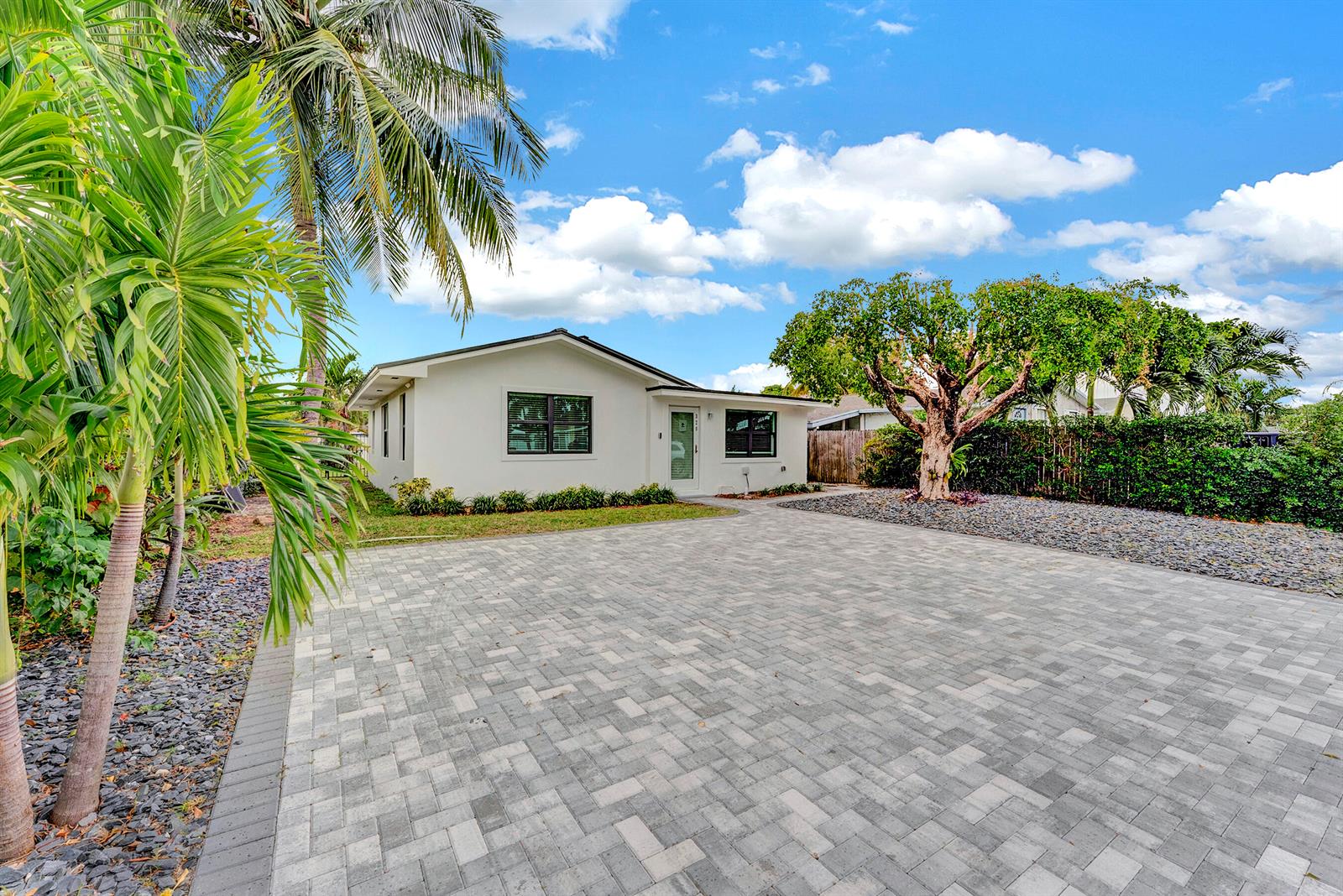 A white single-story house features a large paved driveway, a palm tree, and a mature tree — 320 NW 3rd Avenue, Delray Beach FL 33444, DELRAY BEACH, FL