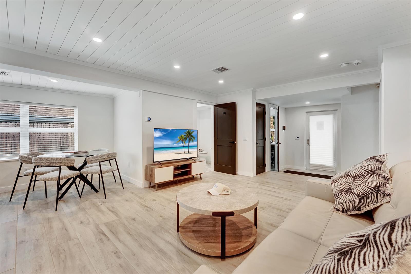 A living room with light wood floors, a round coffee table, and a dining area — 320 NW 3rd Avenue, Delray Beach FL 33444, DELRAY BEACH, FL