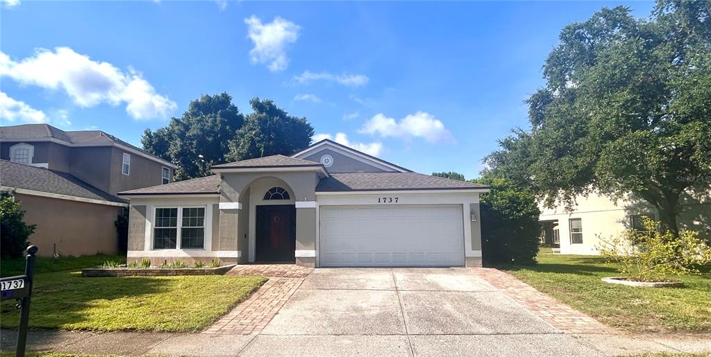 A single-story house features a two-car garage, a paved driveway, and a front entryway — 1737 SETTING SUN LOOP, CASSELBERRY, FL