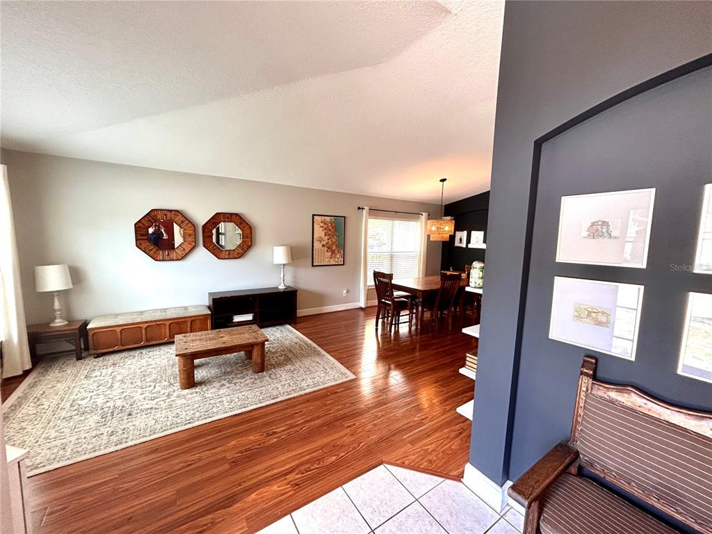 A living and dining area features hardwood floors, a neutral wall color, and dark accents — 1737 SETTING SUN LOOP, CASSELBERRY, FL