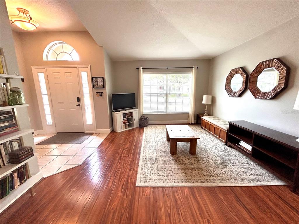 A living room features hardwood floors, a large area rug, and a front entryway — 1737 SETTING SUN LOOP, CASSELBERRY, FL