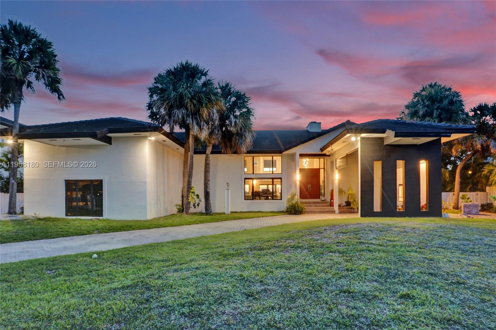 A modern house with white and black exterior walls stands at dusk under a sunset sky — 13724 SW 92nd Ct, Miami FL 33176, MIAMI, FL