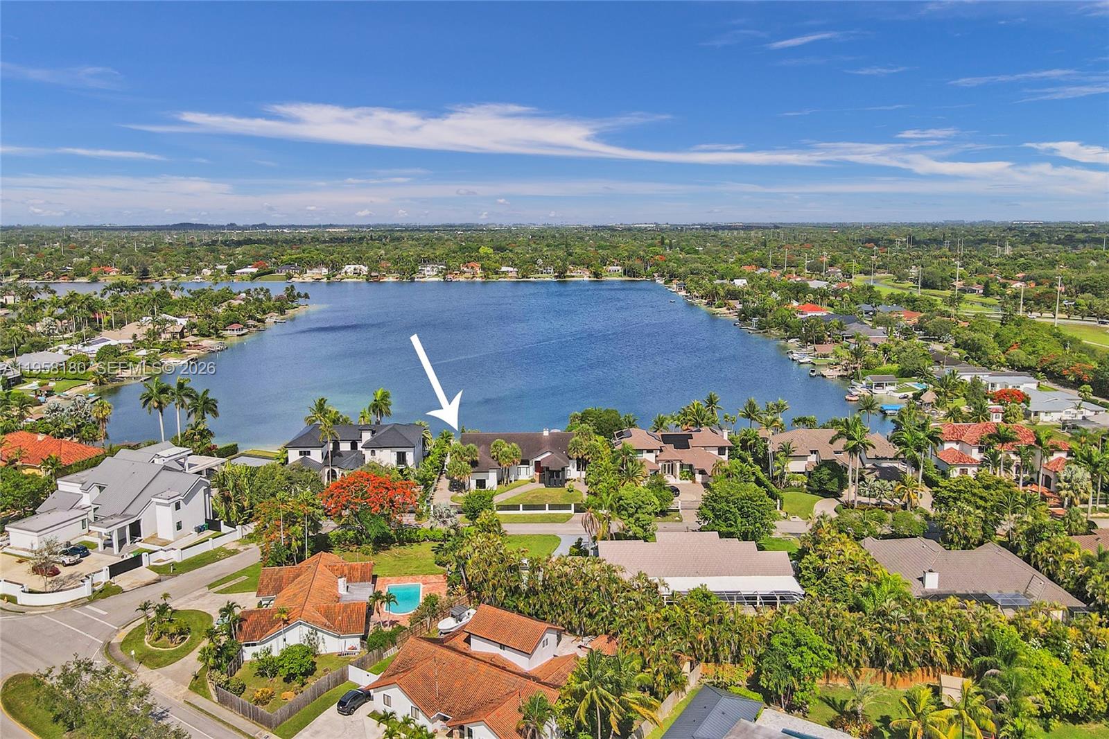 An aerial view shows a waterfront residential neighborhood with a white arrow pointing to a house — 13724 SW 92nd Ct, Miami FL 33176, MIAMI, FL