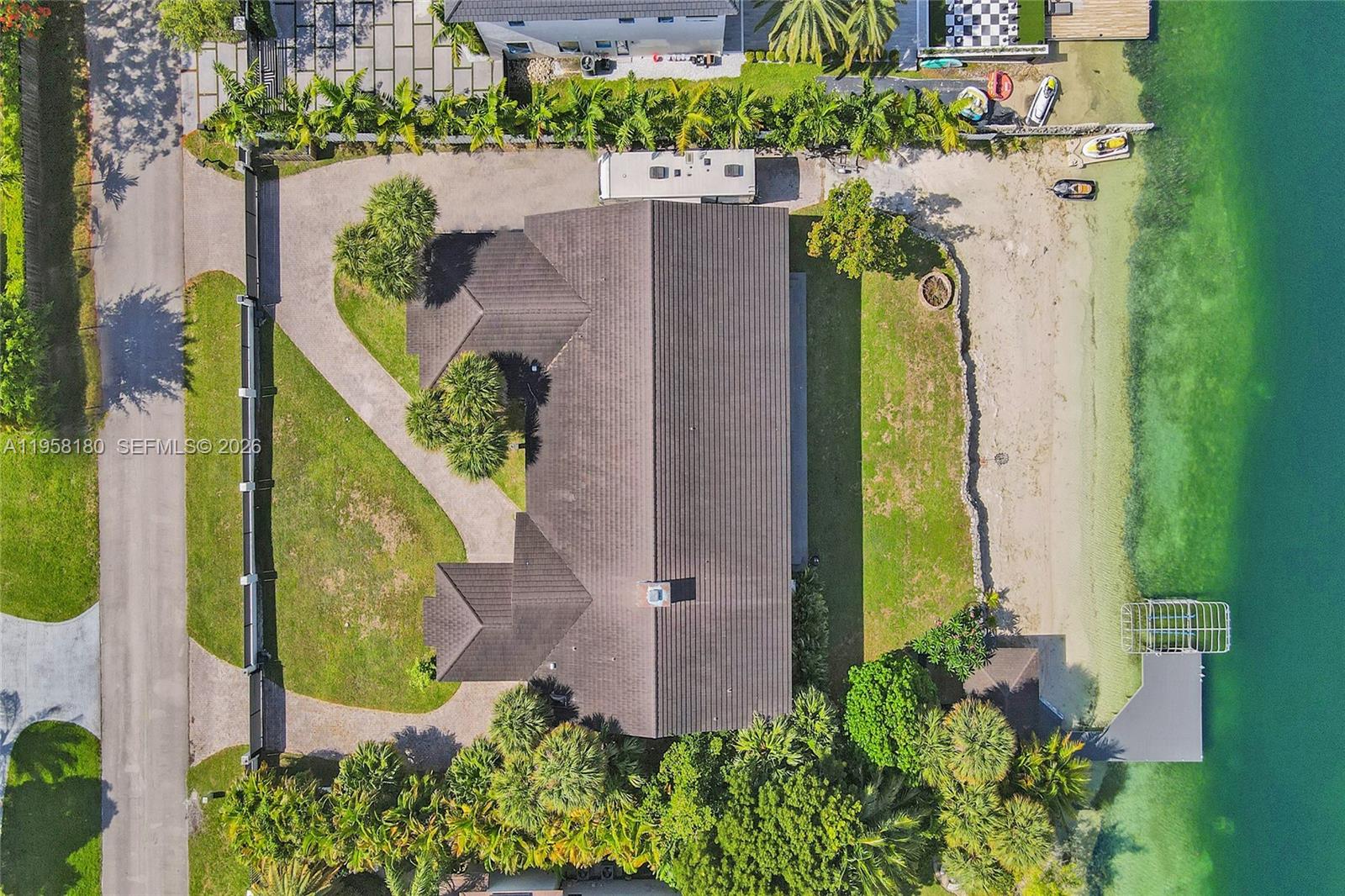 An aerial view shows a house with a dark roof situated on a waterfront lot — 13724 SW 92nd Ct, Miami FL 33176, MIAMI, FL