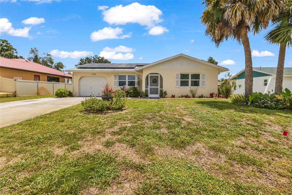 A single-story house with a garage, solar panels, and a front lawn under a blue sky — 1490 DEWITT STREET, PORT CHARLOTTE, FL