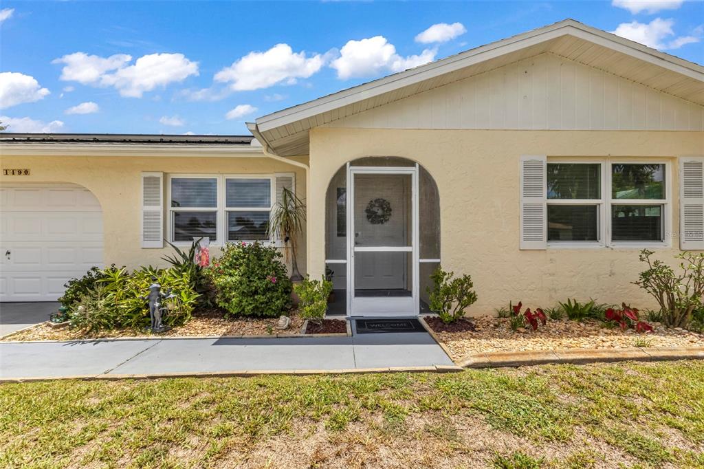 A single-story house with a yellow stucco exterior, a screened arched entryway, and a garage — 1490 DEWITT STREET, PORT CHARLOTTE, FL