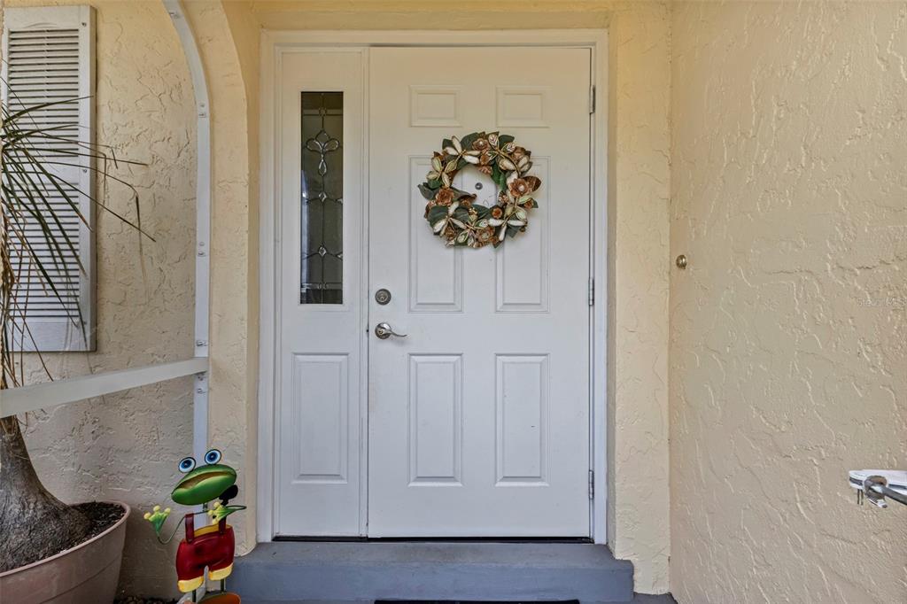 A white front door with a side window and a decorative wreath on a porch — 1490 DEWITT STREET, PORT CHARLOTTE, FL