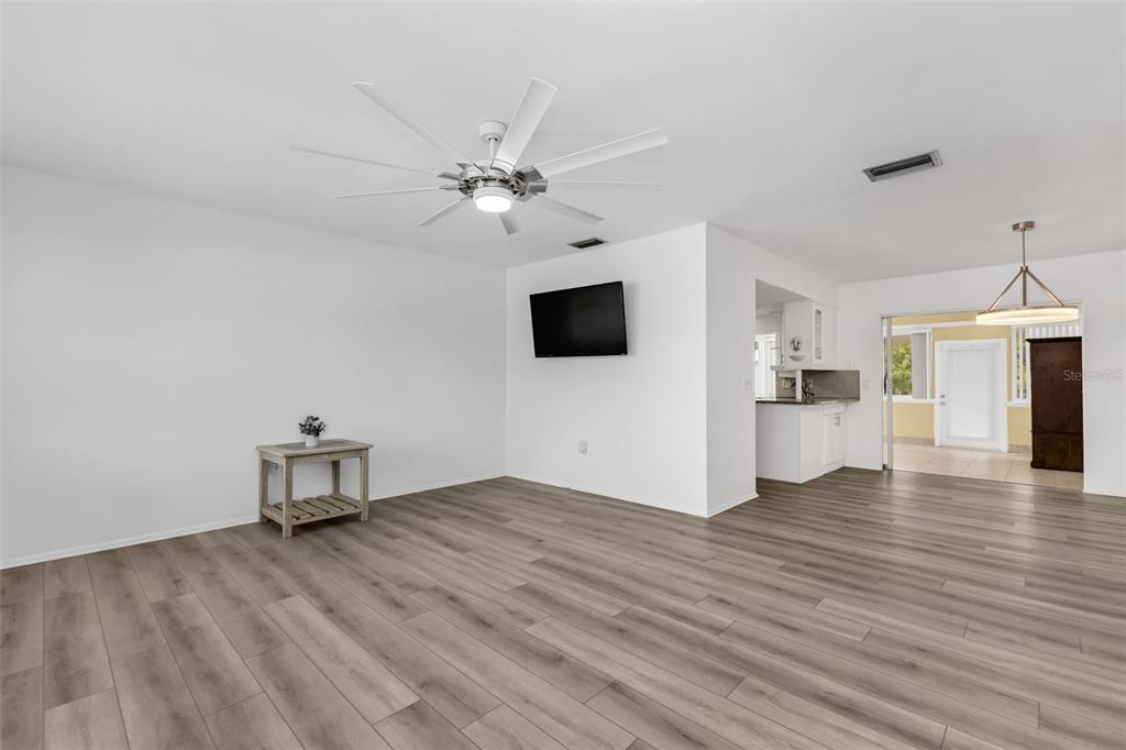 A living room with light wood-look flooring, a ceiling fan, and a wall-mounted television — 1490 DEWITT STREET, PORT CHARLOTTE, FL