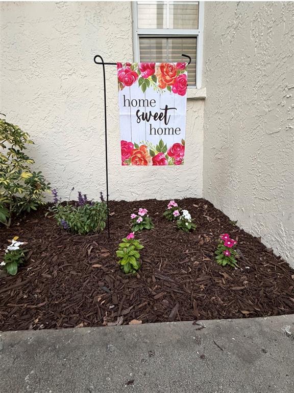 A small garden bed with flowers and a decorative flag sits against a stucco wall — 3815 N OAK DRIVE UNIT G71, TAMPA, FL
