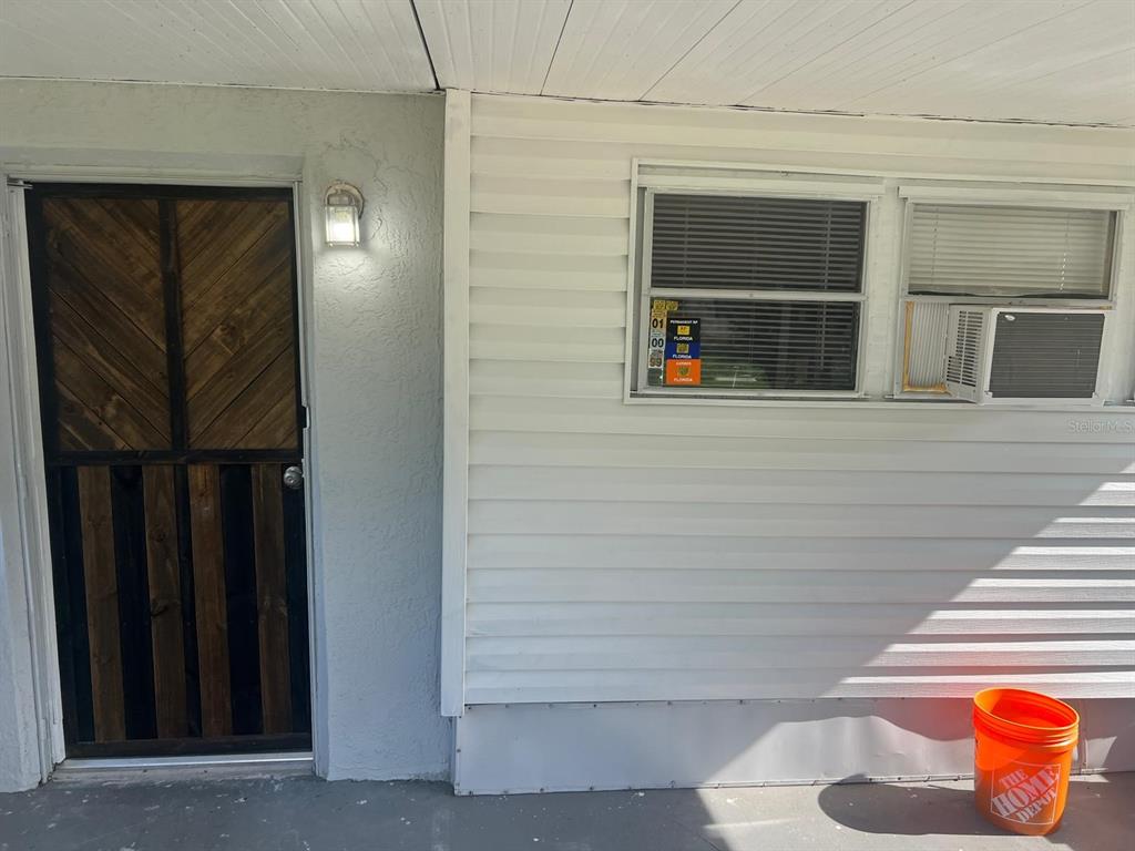 A view of a home exterior featuring a wooden screen door and a window unit — 20456 SE 140TH STREET, UMATILLA, FL