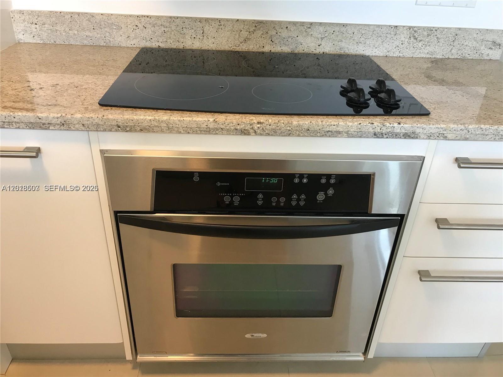 A stainless steel wall oven is installed beneath a black glass cooktop in a kitchen — 185 SW 7th St # 2805, Miami FL 33130, MIAMI, FL