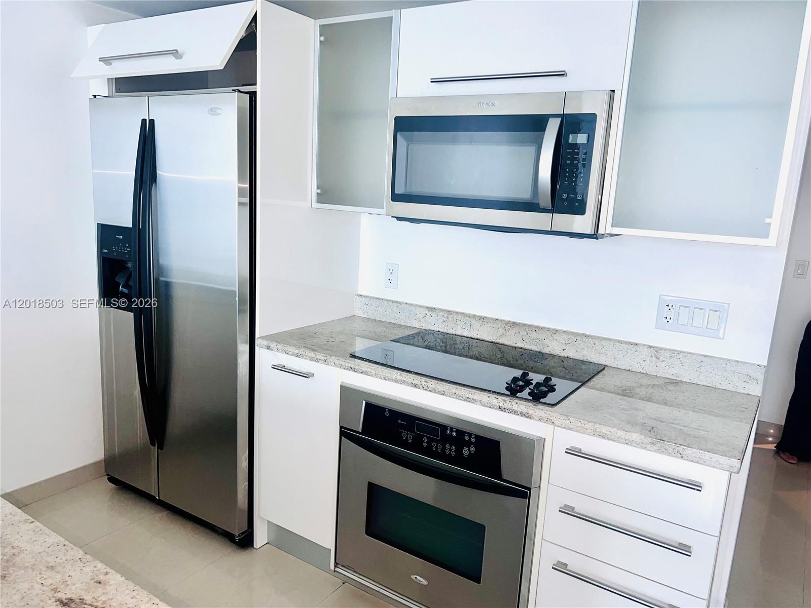 A modern kitchen features white cabinets, stainless steel appliances, and light granite countertops — 185 SW 7th St # 2805, Miami FL 33130, MIAMI, FL