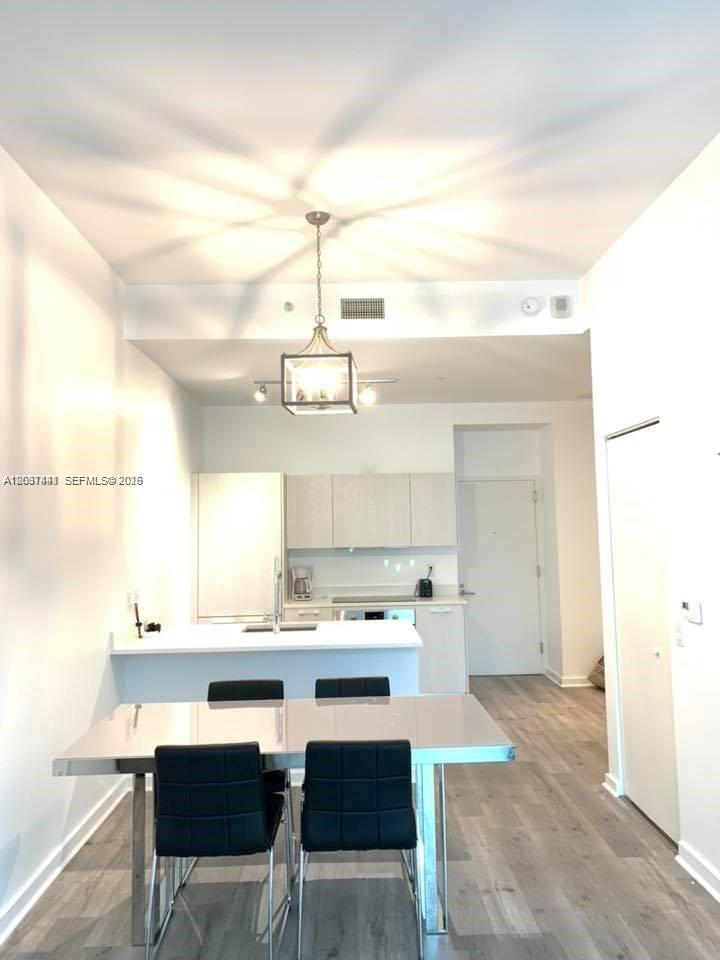 A modern kitchen with white cabinets and a dining table with black chairs — 501 NE 31st St # 202, Miami FL 33137, MIAMI, FL