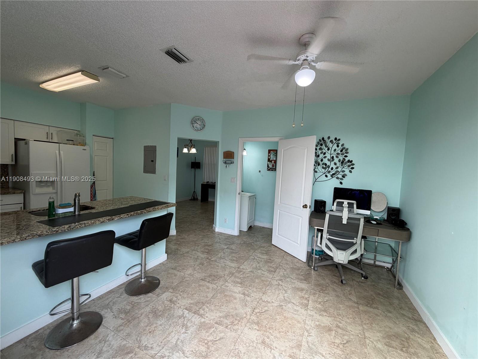 A kitchen with a breakfast bar and an adjacent office area with light blue walls — 810 NE 212th Ter # 2, Miami FL 33179, MIAMI, FL