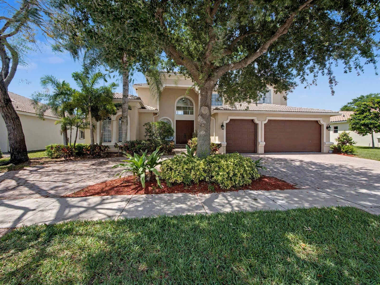 A two-story stucco house with a tile roof, brown garage doors, and a paved driveway — 7244 Vía Abruzzi, Lake Worth FL 33467, LAKE WORTH, FL