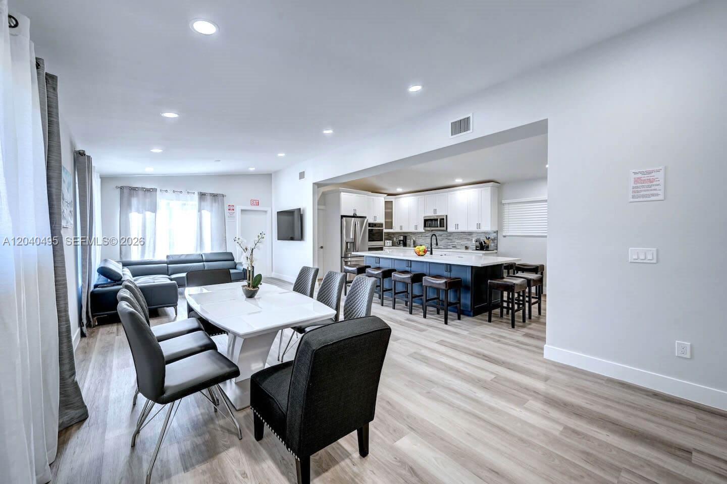 An open-concept living and dining area features a modern kitchen with a large island — HOLLYWOOD, FL