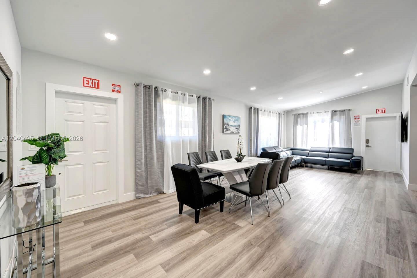 A dining area and living space feature light wood flooring, modern furniture, and white walls — HOLLYWOOD, FL