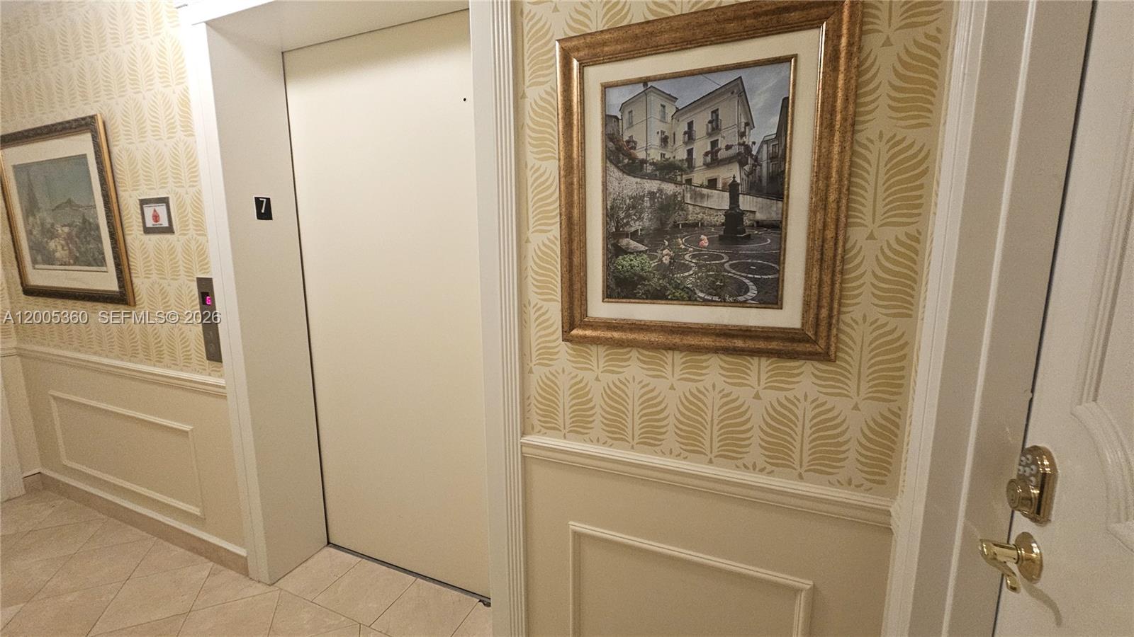 An elevator door is situated between two framed pictures on a patterned wallpapered wall — 4001 N Ocean Blvd # 702, Boca Raton FL 33431, BOCA RATON, FL