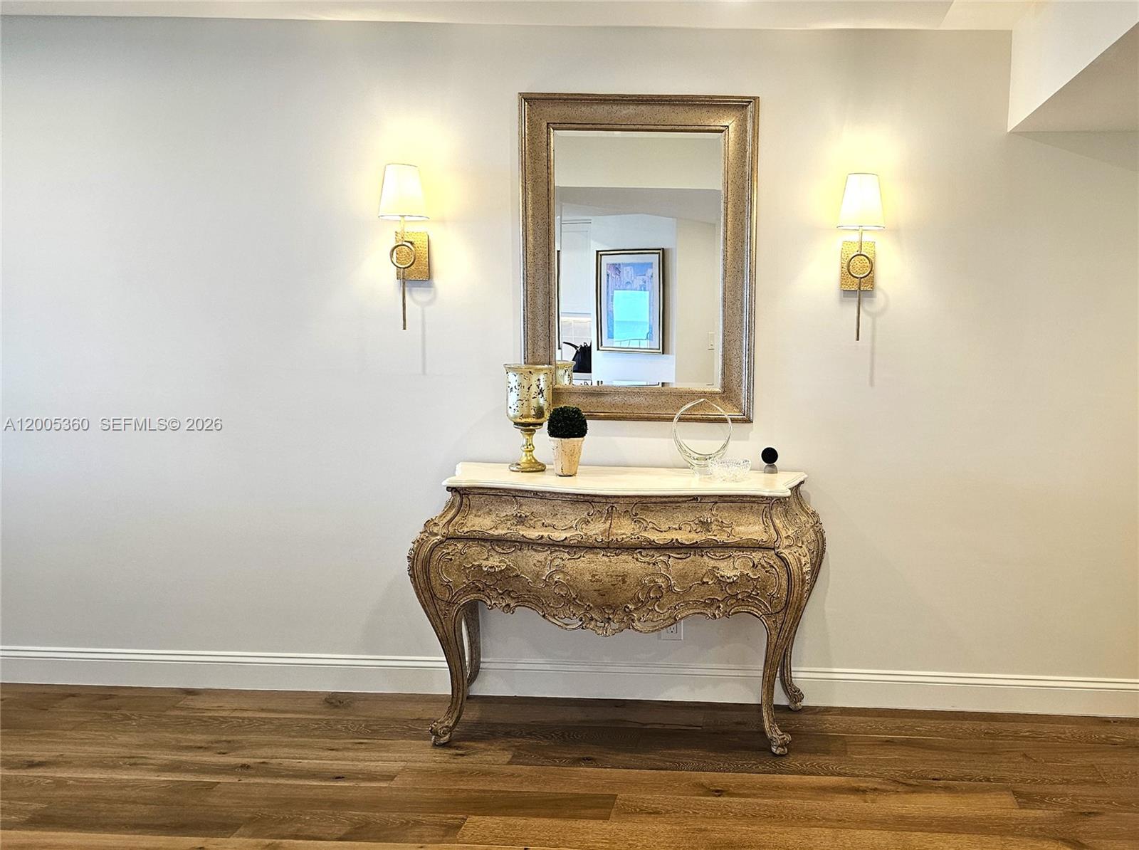 A decorative console table sits beneath a wall mirror flanked by two sconces — 4001 N Ocean Blvd # 702, Boca Raton FL 33431, BOCA RATON, FL
