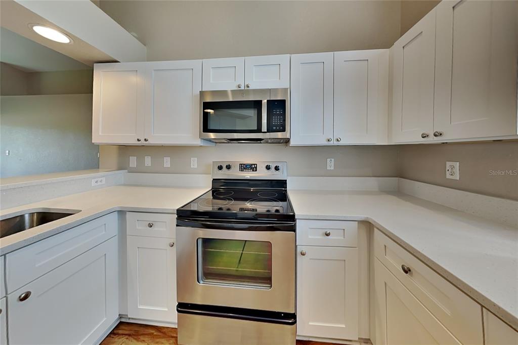 A kitchen features white cabinets, stainless steel appliances, and light-colored countertops — 3382 WINCHESTER ESTATES CIRCLE, LAKELAND, FL