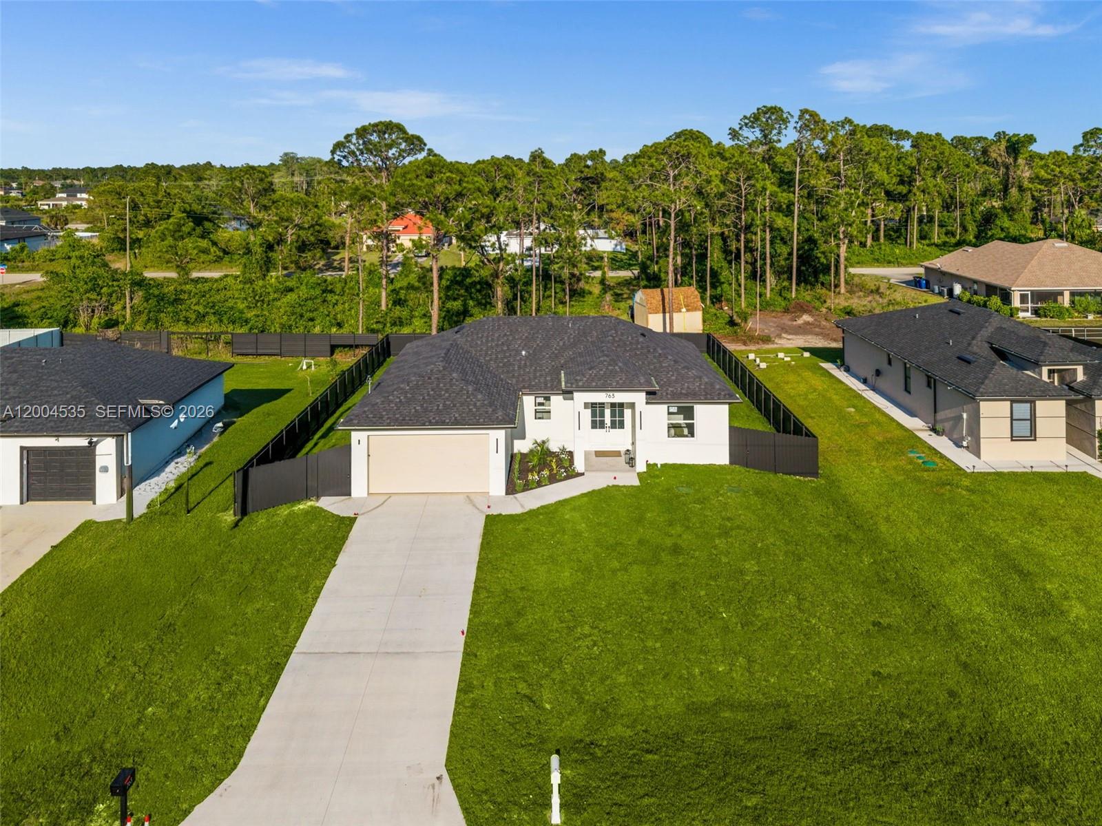 An aerial view shows a single-story white house with a dark roof and fenced yard — 763 Andover Ave S, Lehigh Acres FL 33974, LEHIGH ACRES, FL