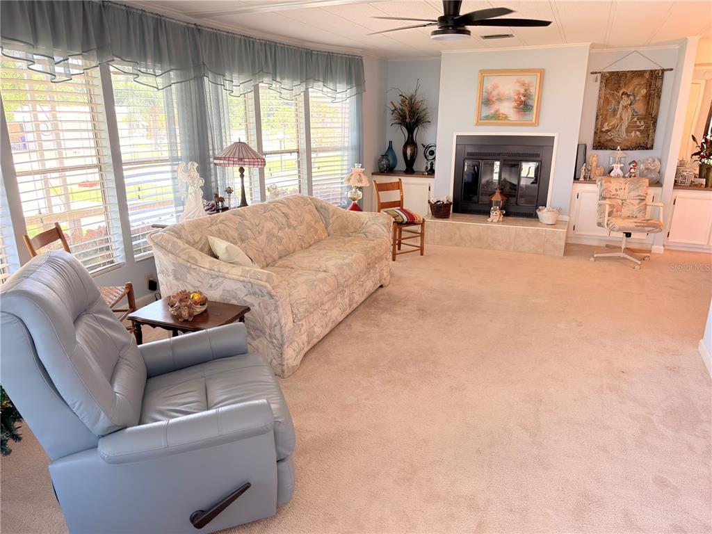 A living room features a fireplace, a floral sofa, a blue recliner, and large windows — 2202 BAHAMA ROAD W, SEBRING, FL