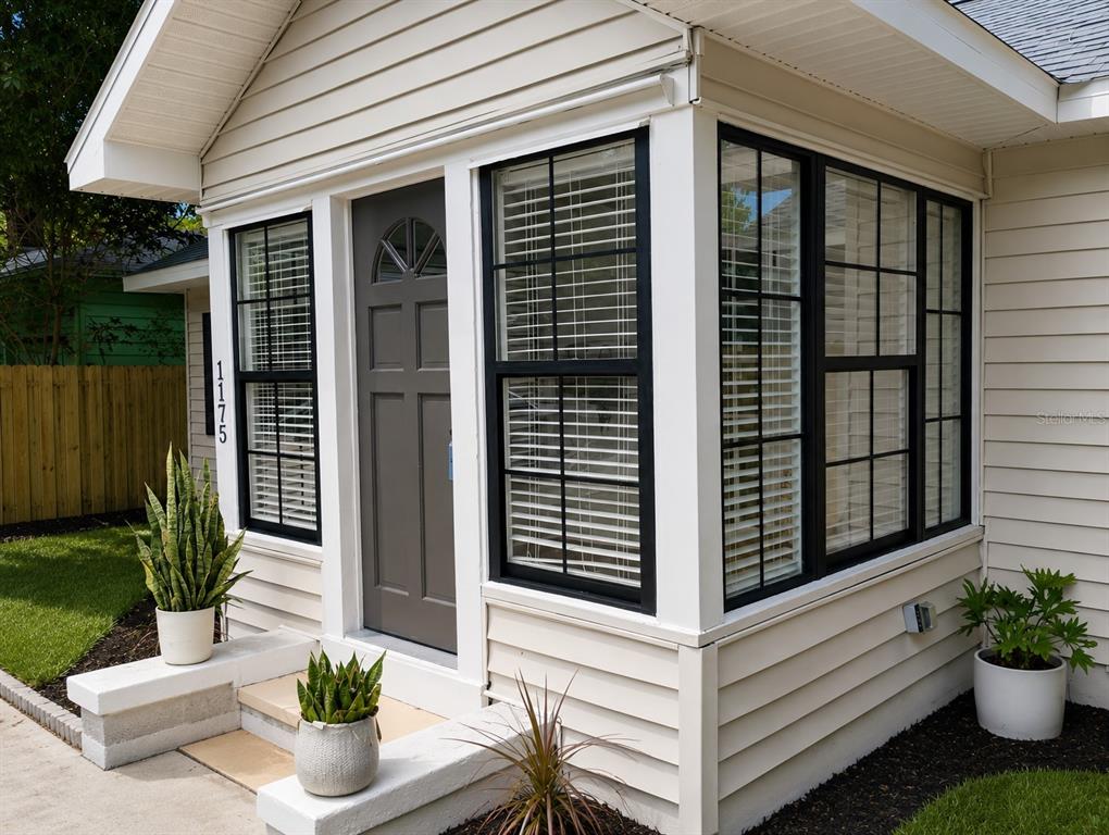 A beige house exterior features a dark gray front door and black-framed windows — 1175 HIGHLAND COURT N, ST PETERSBURG, FL