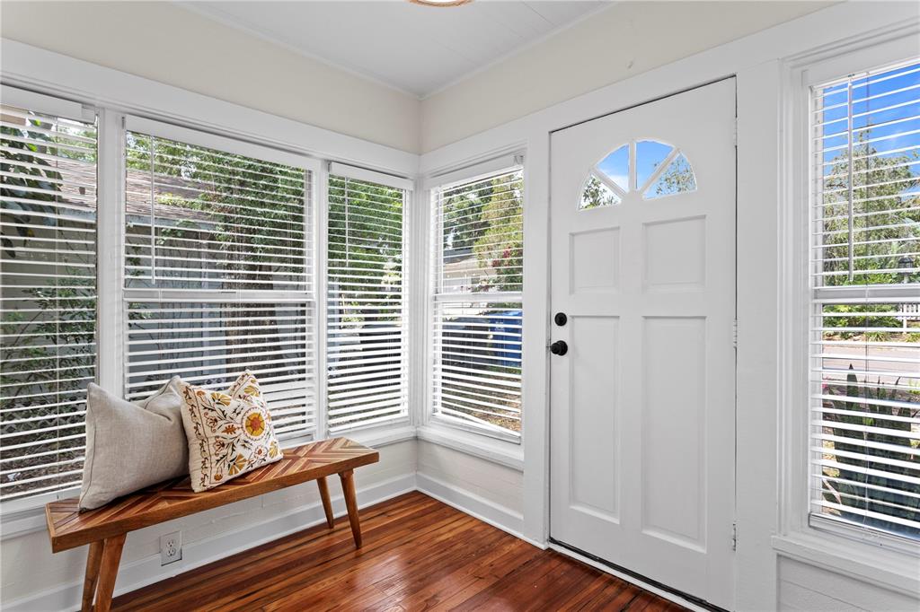 A sunroom features hardwood floors, a wooden bench, multiple windows with blinds, and a door — 1175 HIGHLAND COURT N, ST PETERSBURG, FL