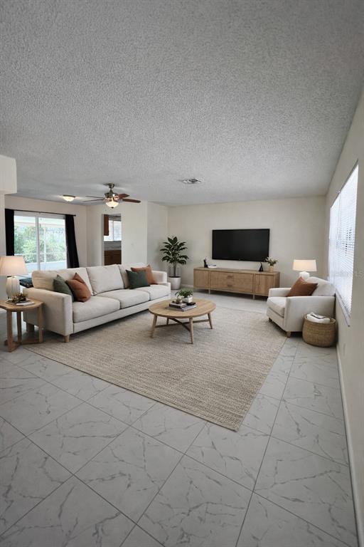 A living room features a beige sofa, a round coffee table, and light-colored tile flooring — 2338 FITZPATRICK TERRACE, DELTONA, FL