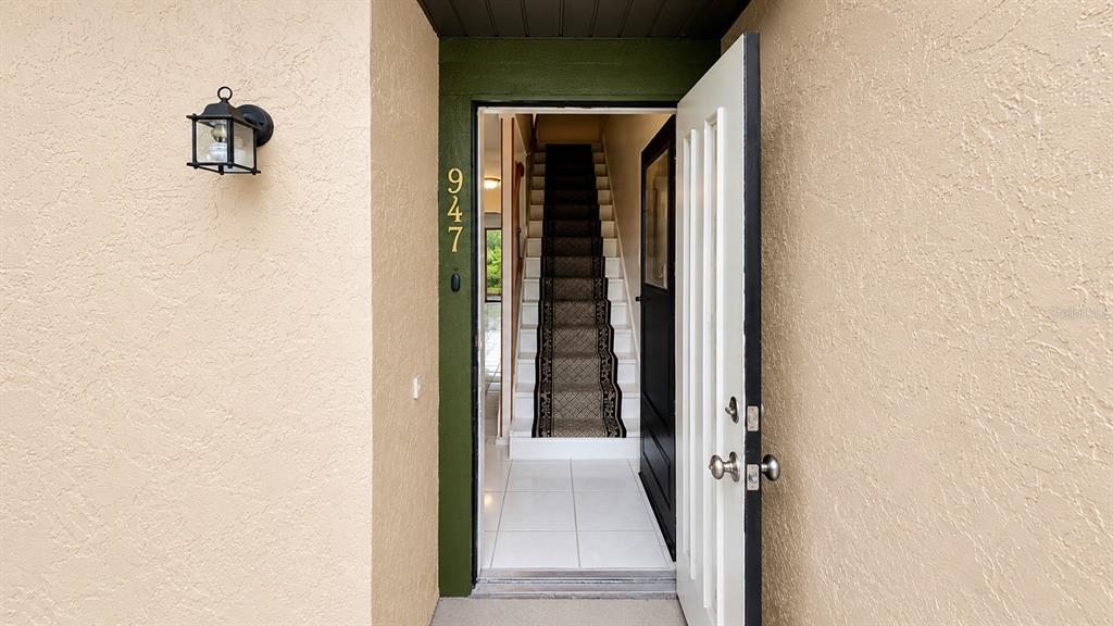 An open front door reveals a tiled entryway and a staircase with a patterned runner — 947 SUNRIDGE WAY UNIT A3, SARASOTA, FL