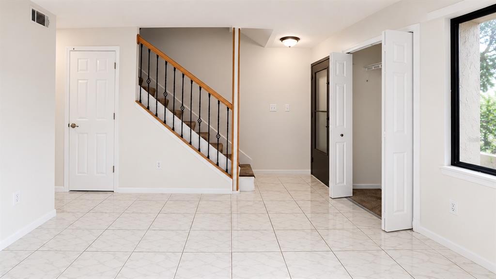 A room with tiled floors, a staircase with iron railings, and a closet with doors — 947 SUNRIDGE WAY UNIT A3, SARASOTA, FL