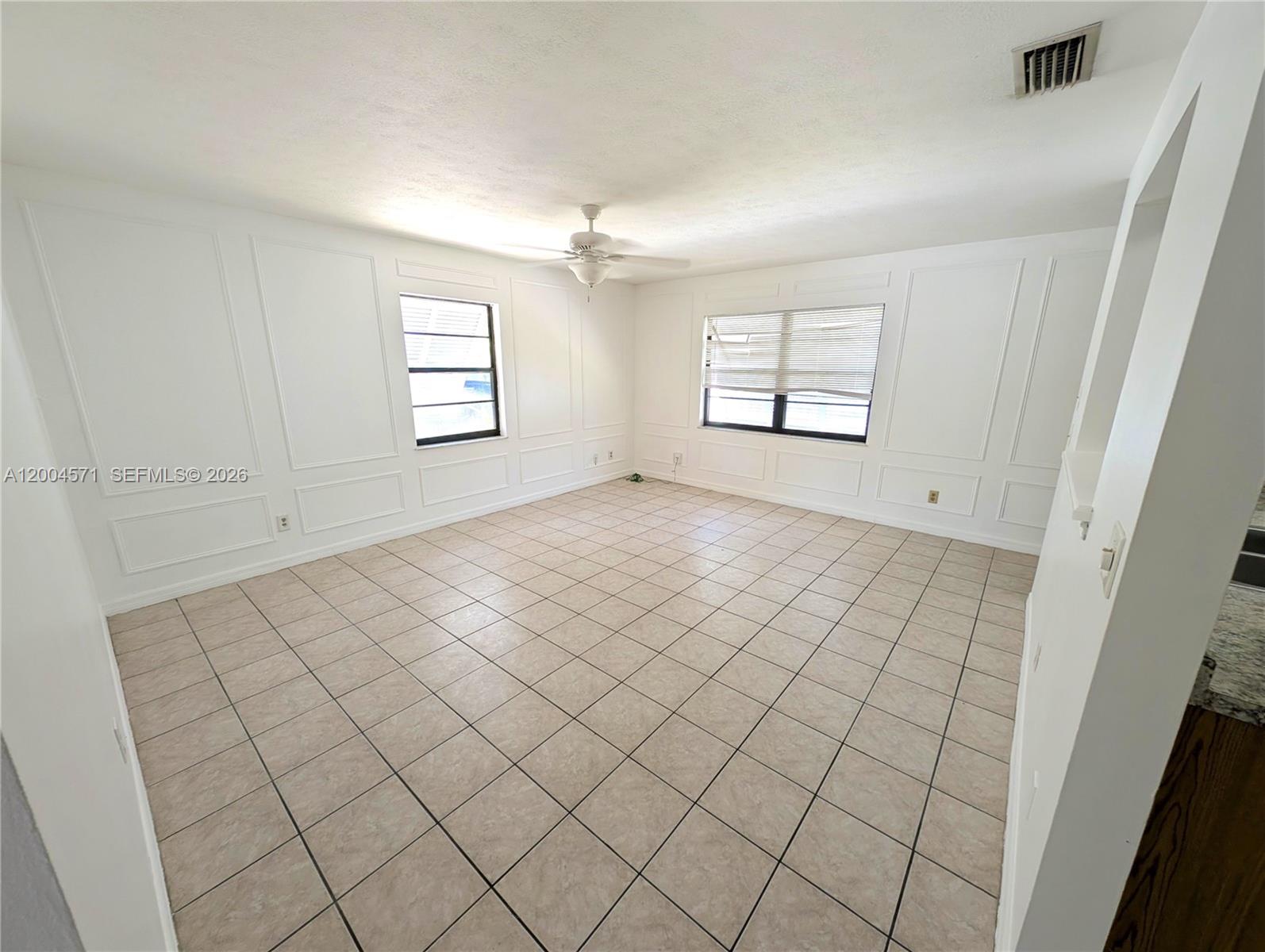An empty room features white wainscoting, beige tile flooring, and a ceiling fan — 915 Turtle Cove Ln, Vero Beach FL 32963, VERO BEACH, FL