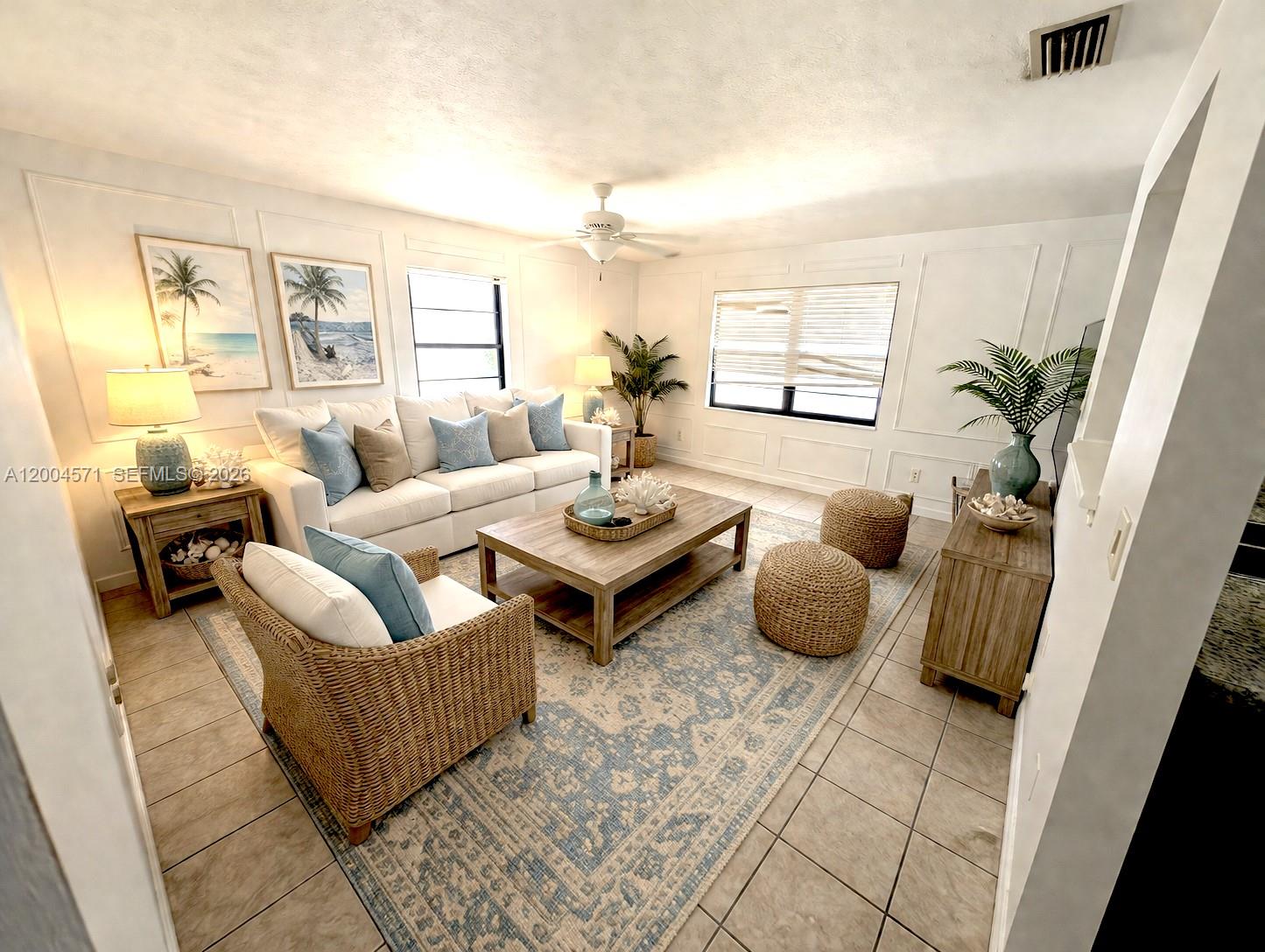 A coastal-style living room features white wainscoting, a blue patterned rug, and wicker furniture — 915 Turtle Cove Ln, Vero Beach FL 32963, VERO BEACH, FL