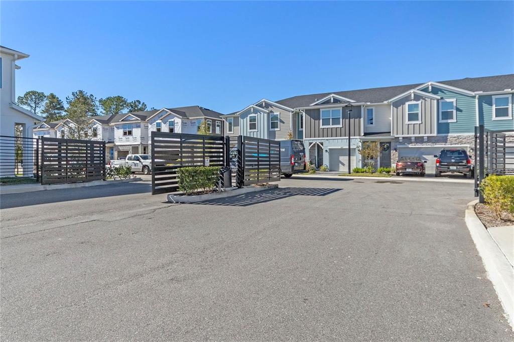 A paved driveway leads to a gated entrance in front of several modern townhomes — 1345 CAPTIVA COVE, SANFORD, FL