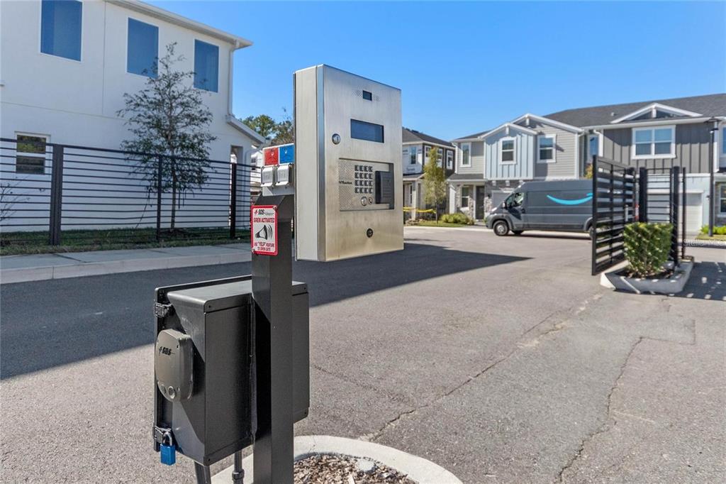 A metal gate access keypad stands on a post in front of a residential street — 1345 CAPTIVA COVE, SANFORD, FL