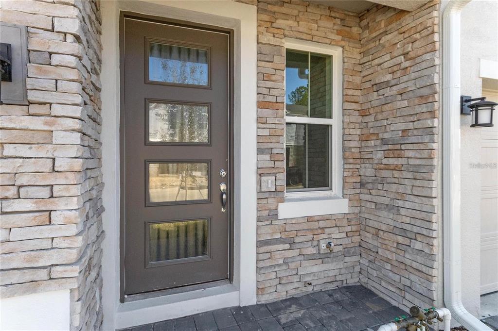 A front entryway features a dark brown door with four glass panels and stone veneer siding — 1345 CAPTIVA COVE, SANFORD, FL