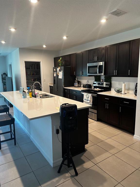 A kitchen features dark wood cabinets, white countertops, a large island, and tile flooring — 4762 VELLACITO WAY, DAVENPORT, FL