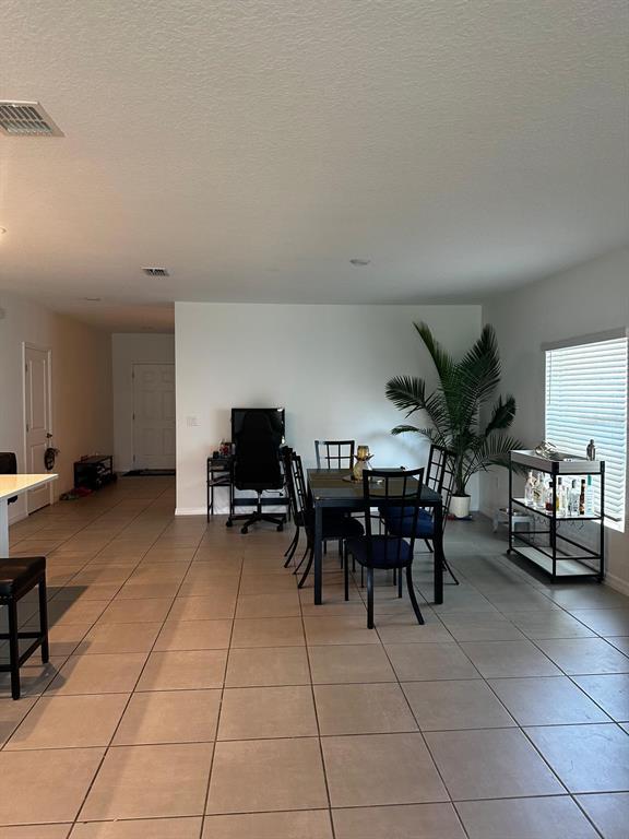 A dining area with a table, chairs, a computer desk, and a bar cart on tile — 4762 VELLACITO WAY, DAVENPORT, FL